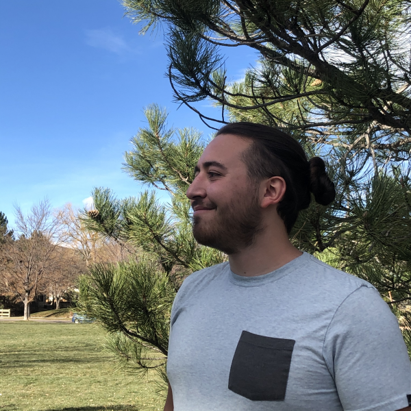 A profile photo of Caleb Wexler in a grassy field in front of a pine tree