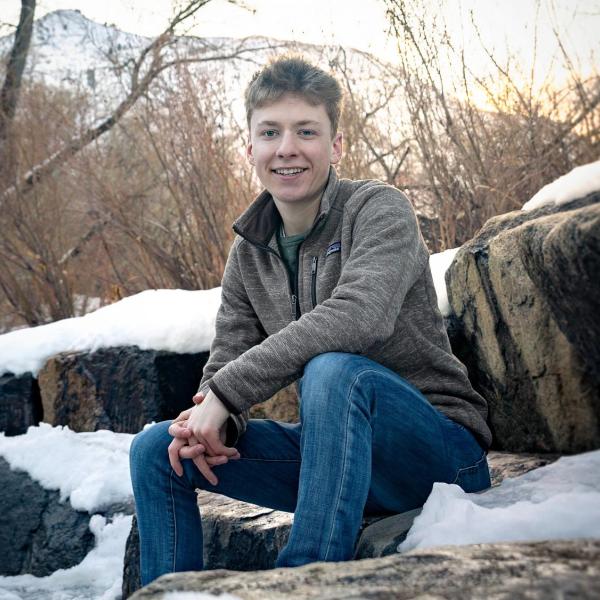 Maximilian Chambers sits on top of icy rocks. 
