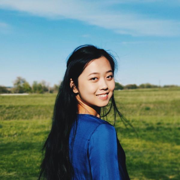 Chang Liu smiles from a green field of grass