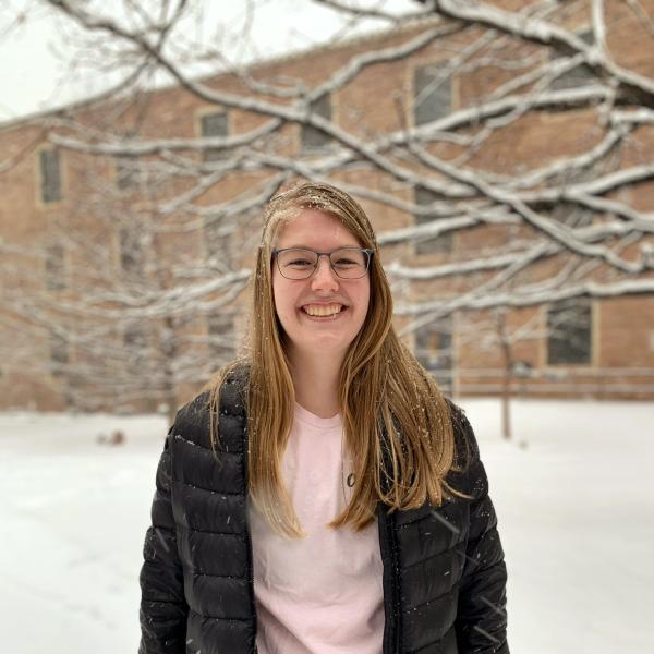 Taylor Christiansen stands in front of a tree. 