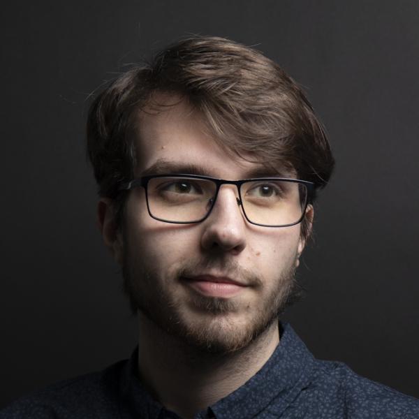 Philip Coleman stands in front of a gray wall.