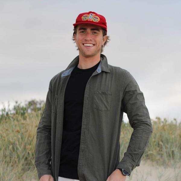 Drew Brown wearing a red baseball cap and standing among grasses