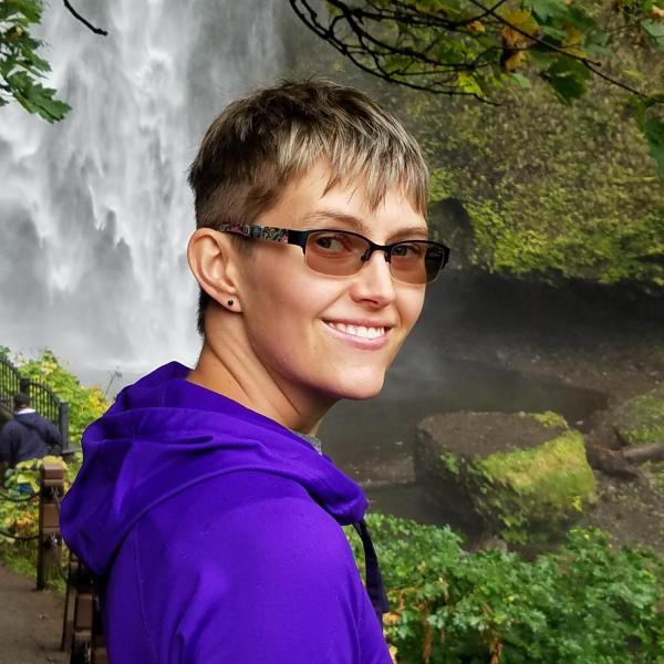 Erin Phares smiles with a waterfall and greenery in the background
