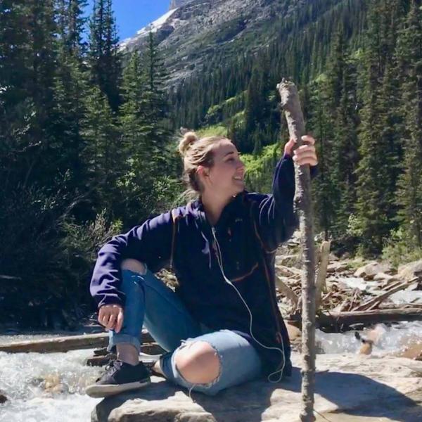 A. Bryce Fausnaught sits on a rock in front of trees.