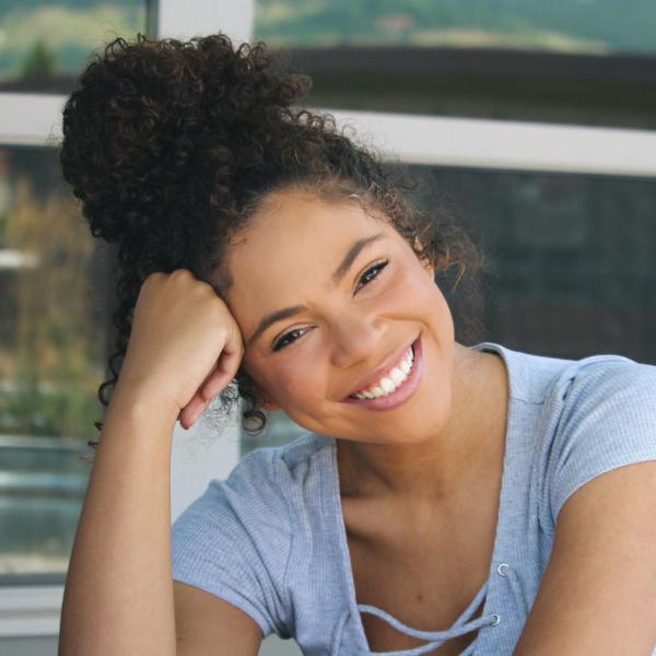 Audre Greer sits in a chair in front of a window.