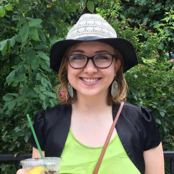 Hannah Briner smiles and holds a cup of lemon water