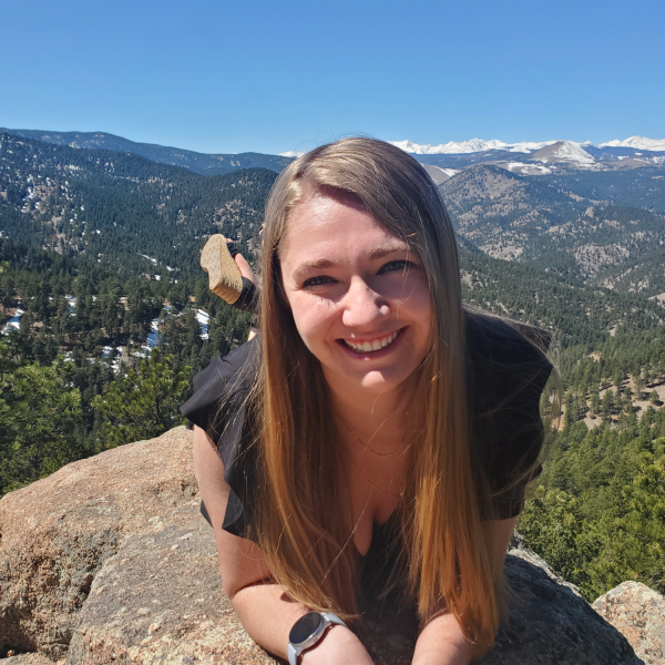 Emily Hay-Arthur lays on a rock in front of mountains.