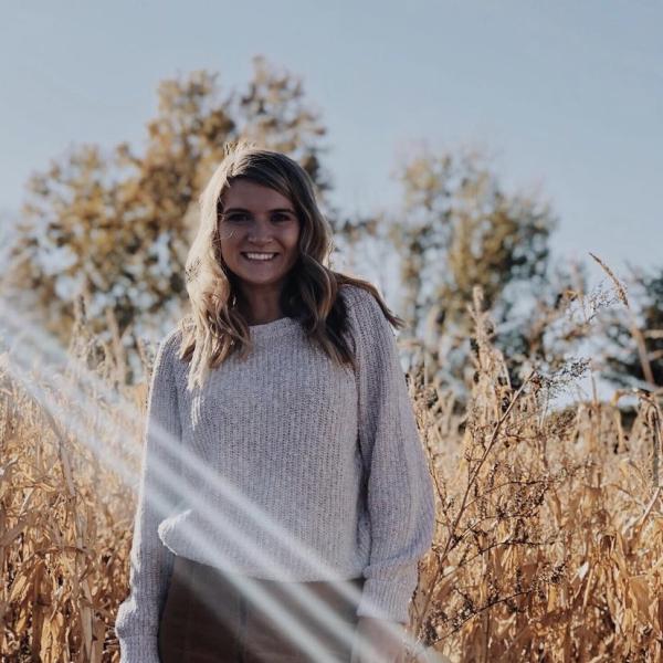 Haley Heinzelman stands in front of a field of grain.