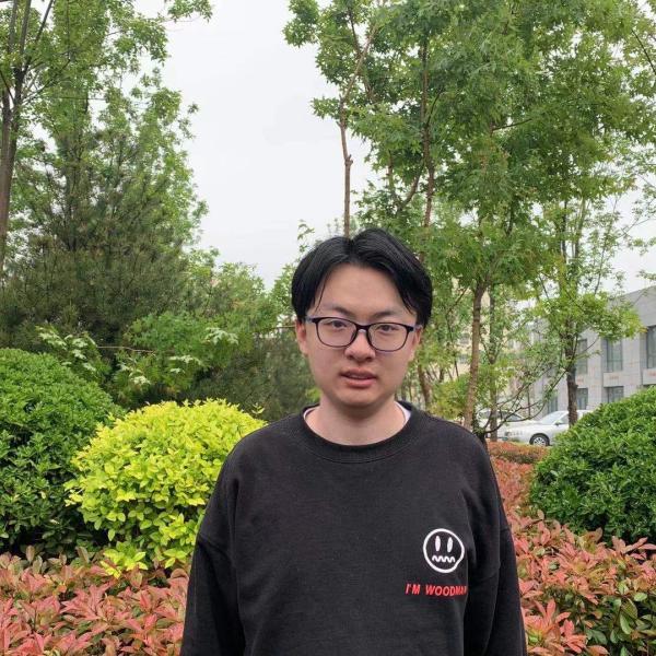 Cheng Jiang stands in front of trees.