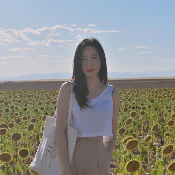 Mia Kim stands in front of a flower garden.