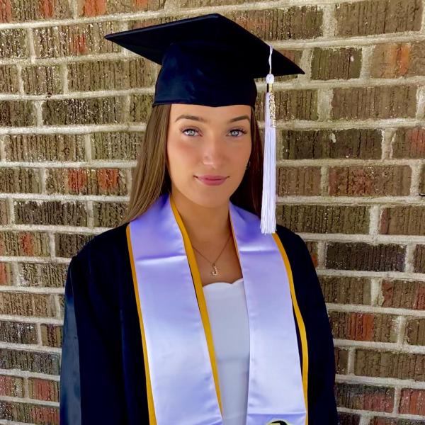 Joanna Kristensen stands in front of brick wall.