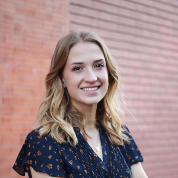 Hannah Kuhn-Gale stands in front of brick wall.