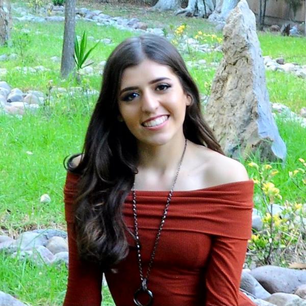 Kimberly Lozano Casas with grass, flowers, and rocks in background.