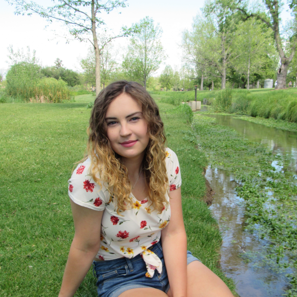 Mika Mildenberger sits on grass next to a body of water.