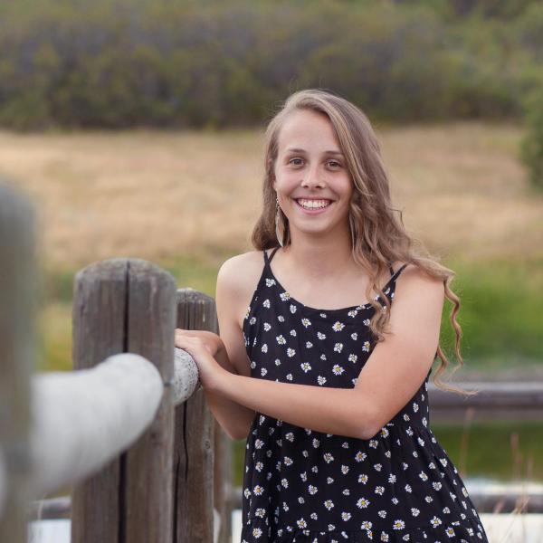 Alexis Montague stands next to a wooden fence.