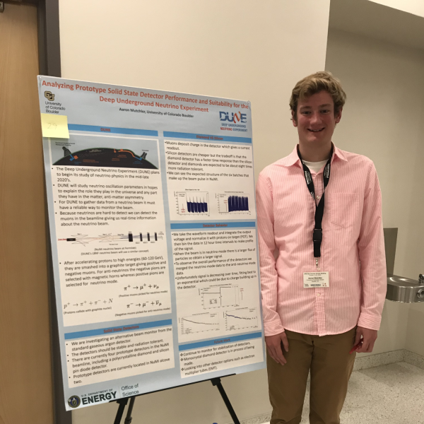 Aaron Mutchler stands next to a poster.