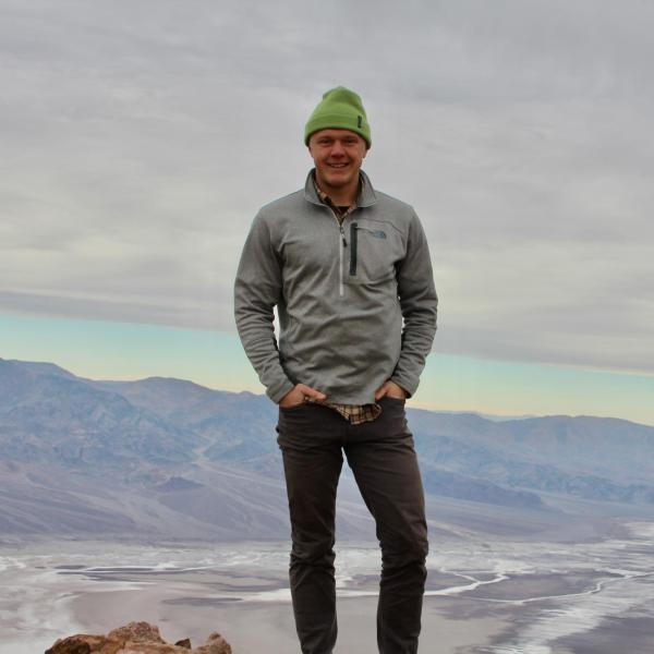 Cole Skilbred stands in front of a mountain.