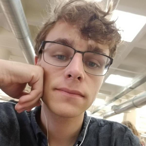 Dylan Wharton wears a dark button-down shirt and glasses