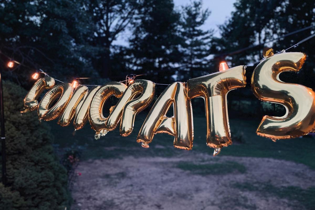 Metallic gold ballons spell out "Congrats"