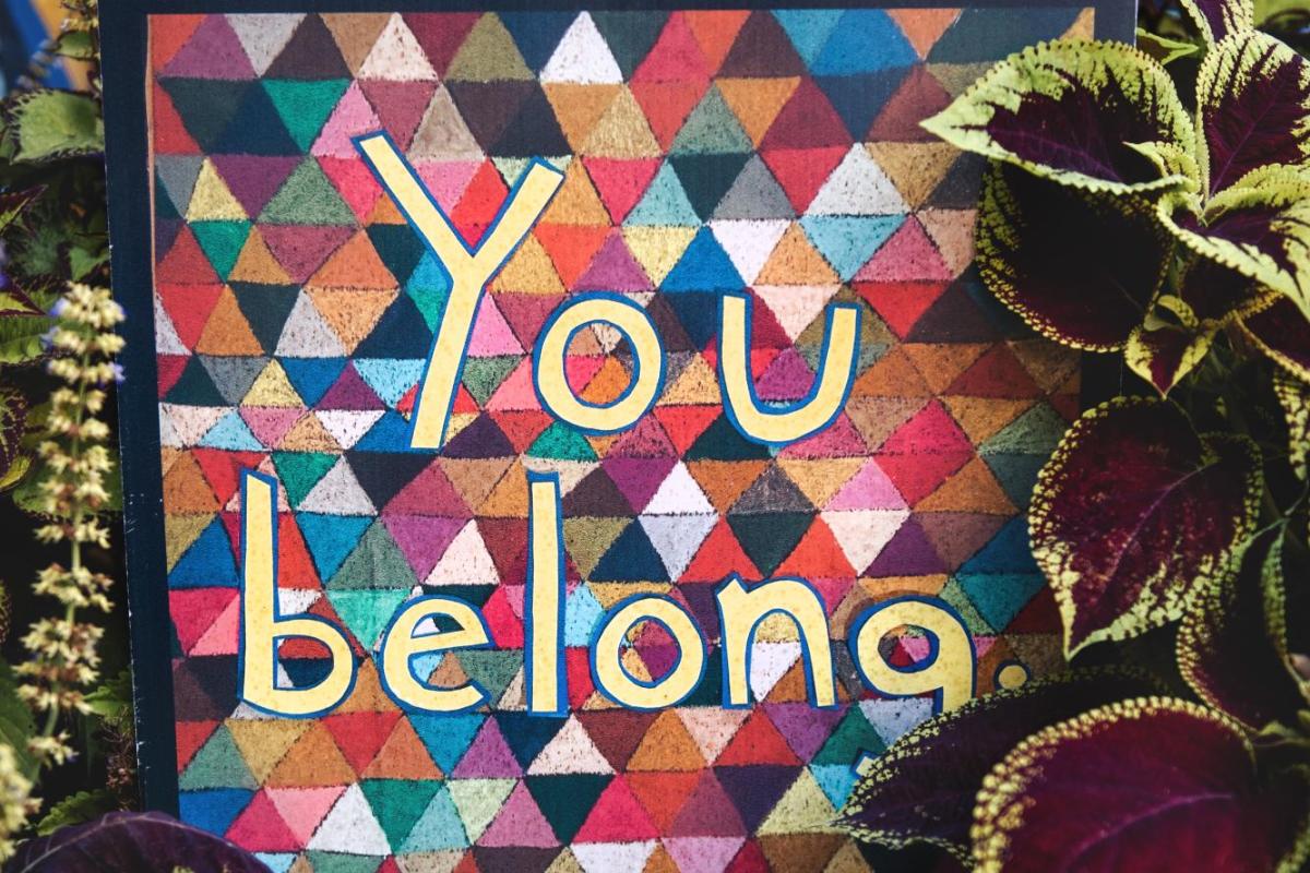 Colorful triangle-patterned background with "You belong" written on it