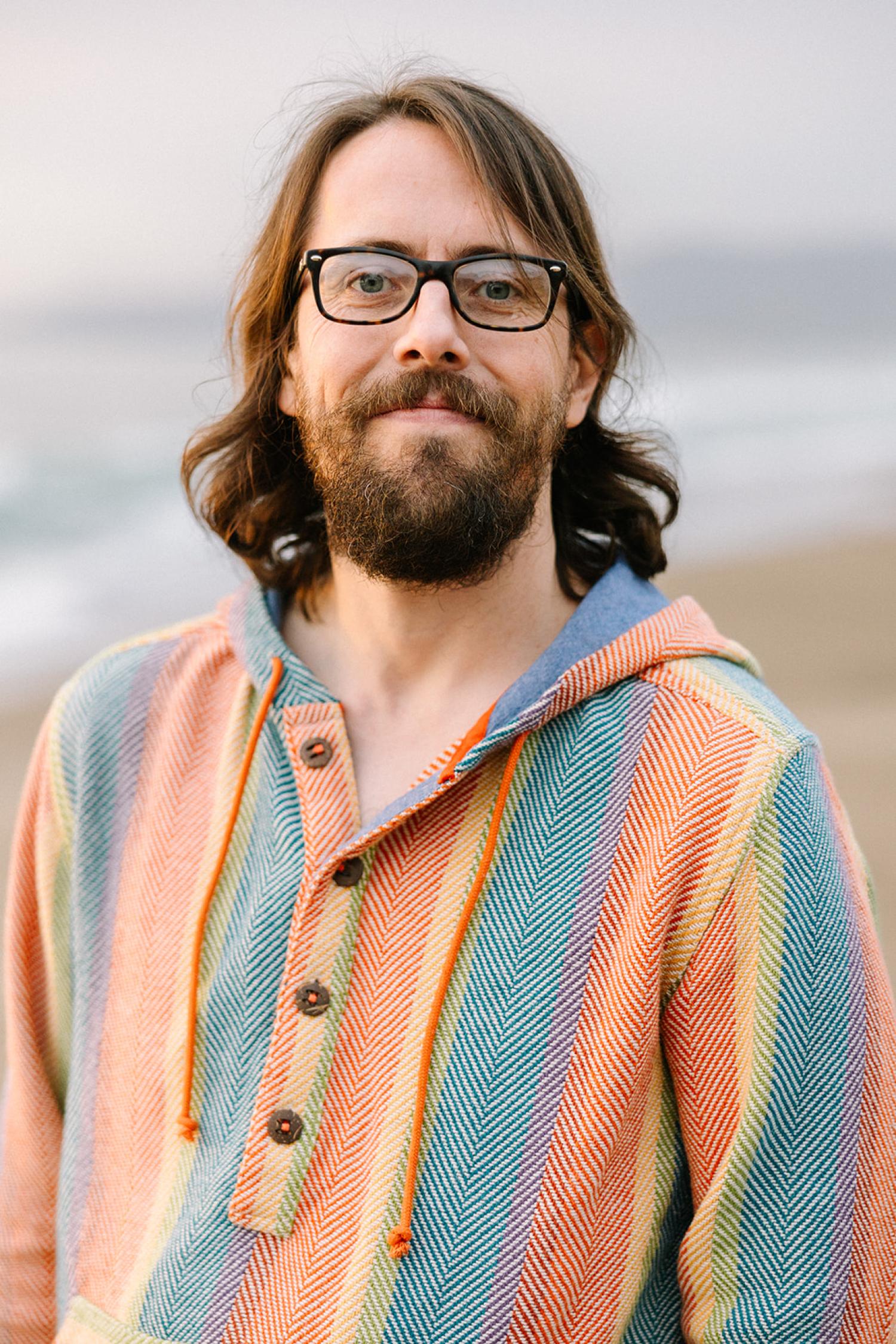 Braden smiling and wearing a multicolored shirt and glasses