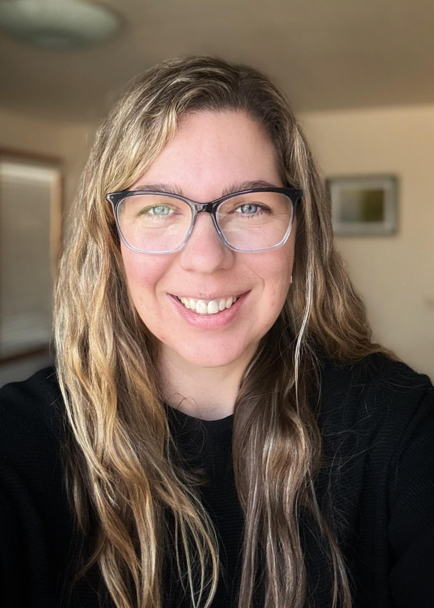 Maureen smiling and wearing a black shirt and glasses