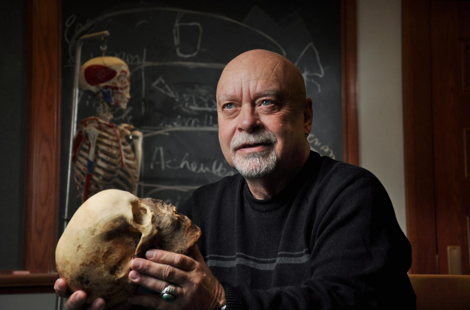 Anthropologist and former Honors Director Dennis Van Gerven holding a human skull.