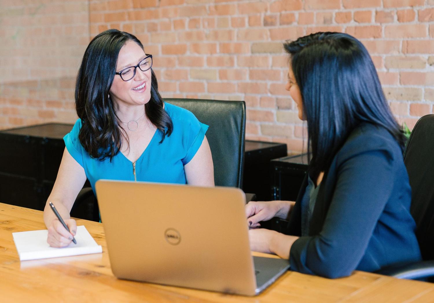 Two women talking, while one takes notes on a notepad