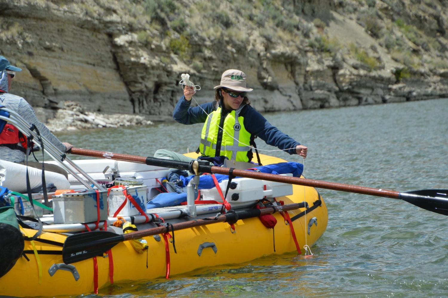 Person on inflatable boat in a river taking a water sample
