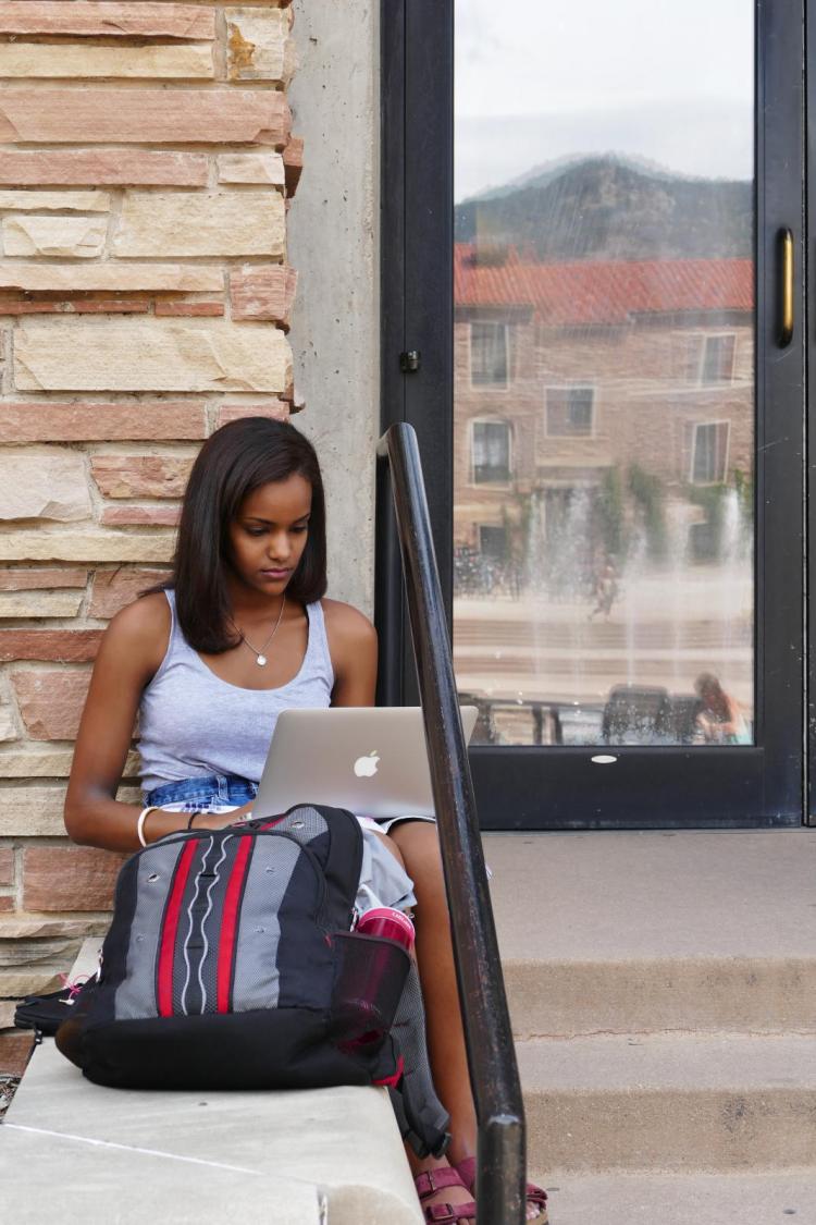 Student using laptop on outside steps of a CU building