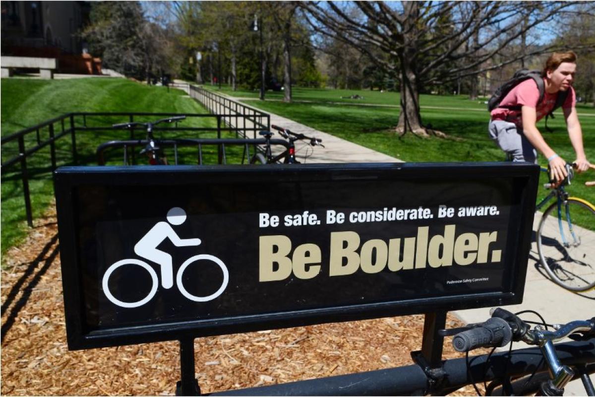 Be Boulder sign and student riding a bike