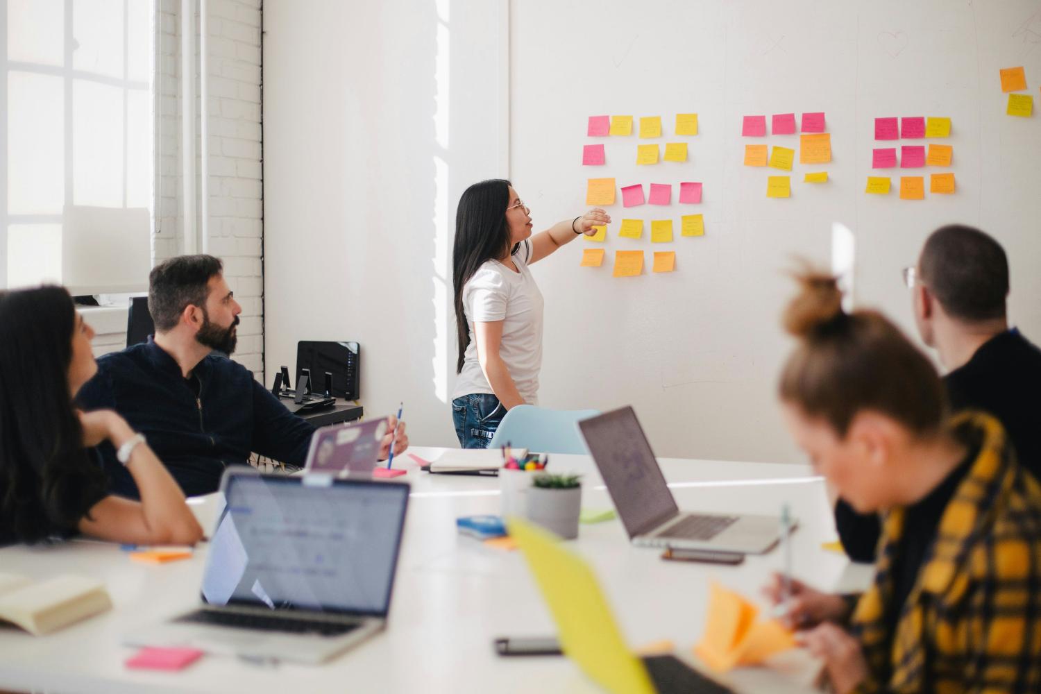 people talking in a conference room looking at sticky notes on the wall