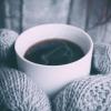 Mittens holding a hot beverage
