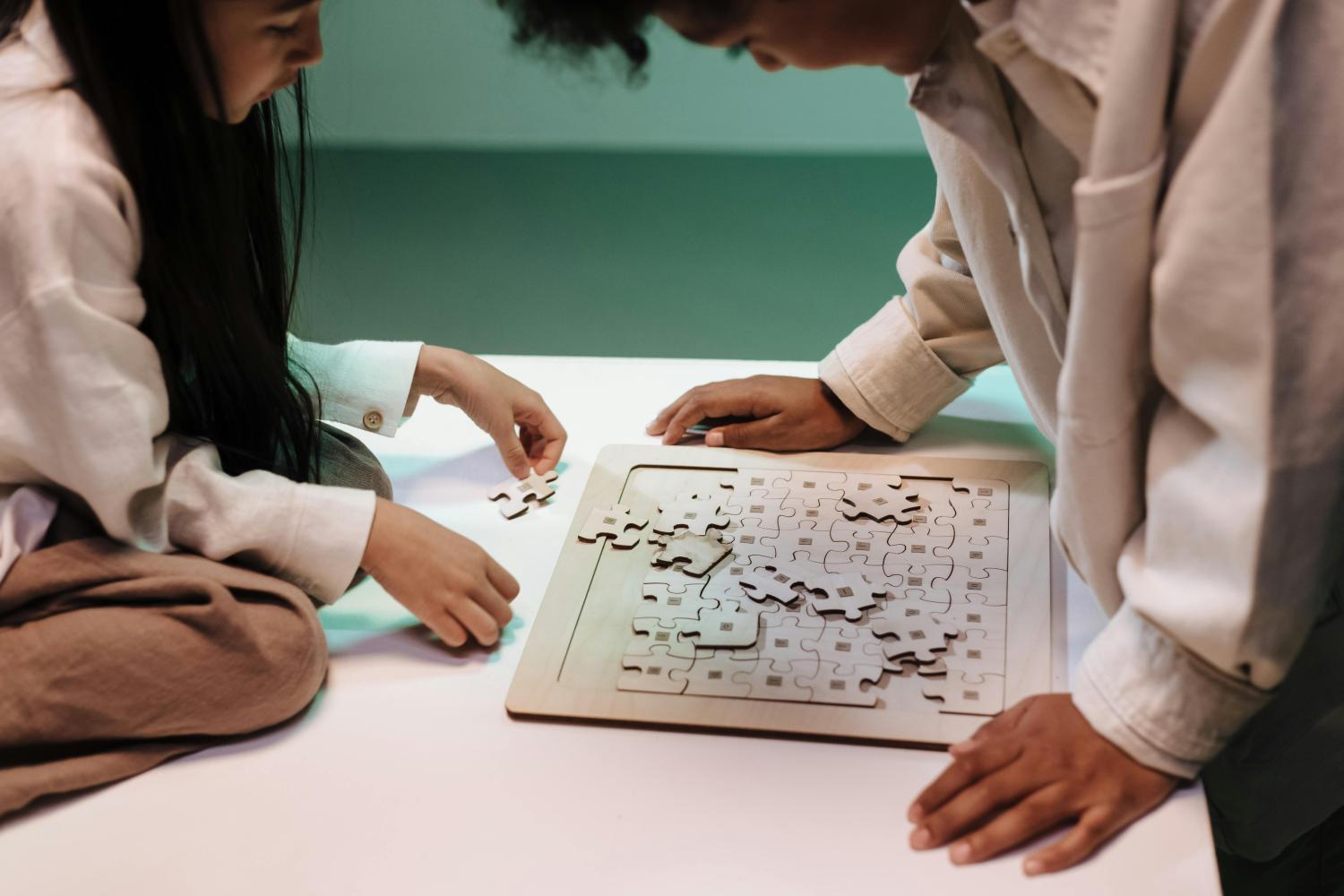 Two young people working on a jigsaw puzzle together, as if solving a moral dilemma.