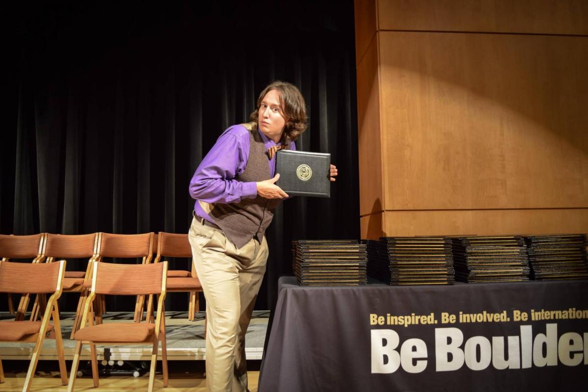 advisor gabe holding up diploma at graduation ceremony
