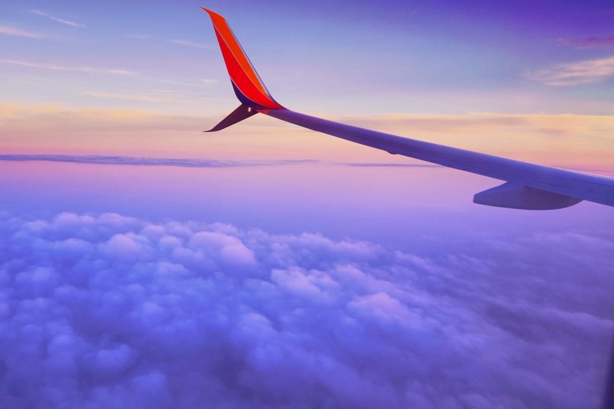 wing of an airplane with clouds and sunset behind