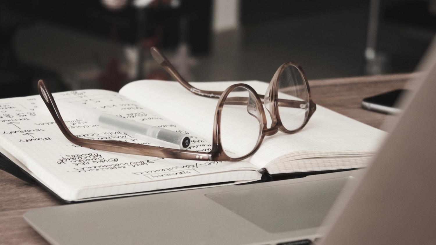 Pair of glasses on a book with writing