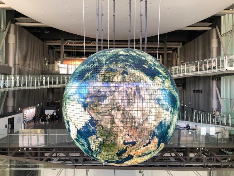 large globe hanging from the ceiling in a glass staircase area.