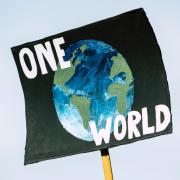 sign with painting of earth and words "one world"