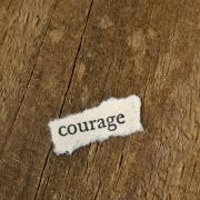 wood background with piece of paper that says courage