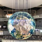 large globe hanging from the ceiling in a glass staircase area. 