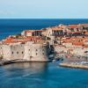 A historic coastal city with medieval stone walls, terracotta roofs, a harbor with boats, and the Adriatic Sea under a clear, sunny sky. Photo by Ivan Ivankovic on Unsplash