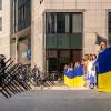 a-group-of-people-in-clothing-outside-a-building holding ukrainian flags