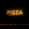 yellow neon sign that says Pizza