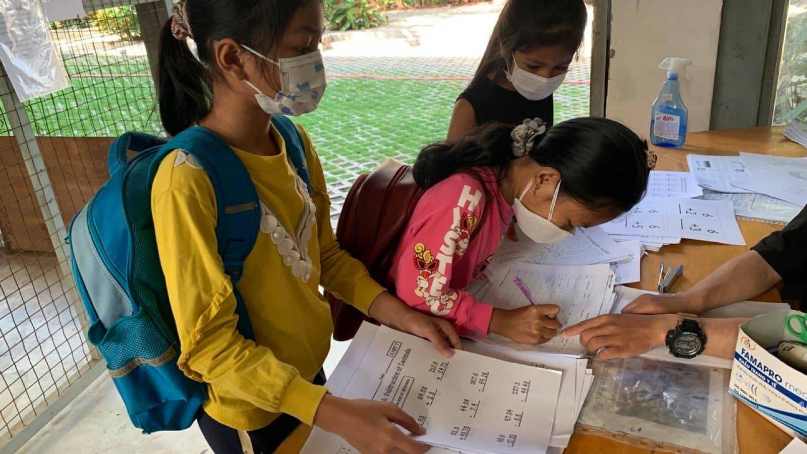 students receiving homework packets in Phnom Penh, Cambodia during the COVID-19 pandemic