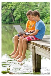 Young twin boys looking at laptop on pier