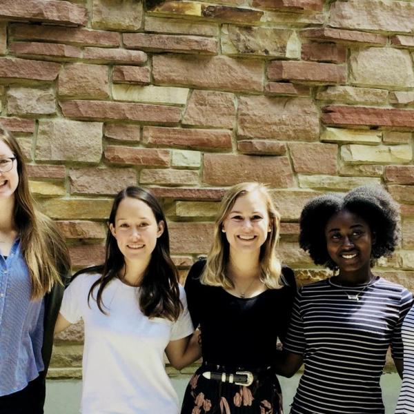 Lab researchers pose in front of a stone wall