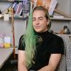 Morgan Klaus Scheuerman sits on a chair at a desk.