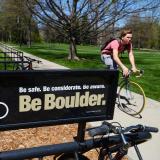 biker on campus with Be Boulder sign