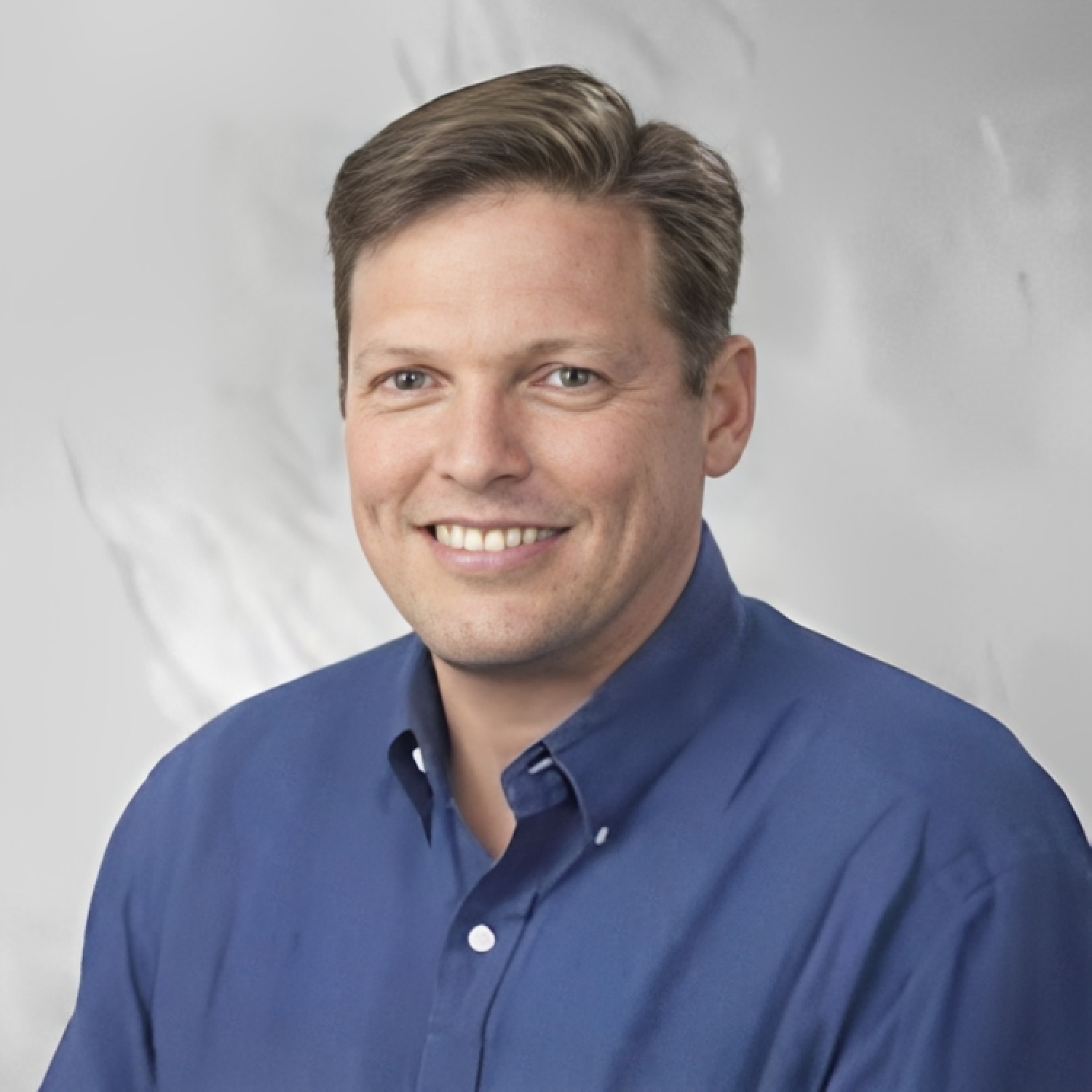 Photo of Brent Willis smiling with a blue button up shirt.